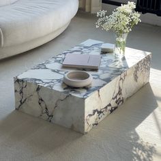 a marble coffee table with a book and vase on it