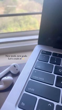 an open laptop computer sitting on top of a wooden desk next to a pair of headphones