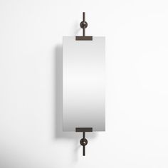 a mirror mounted to the side of a wall with an iron hook on it's end