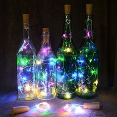 three bottles with lights in them are sitting on the floor next to some corks