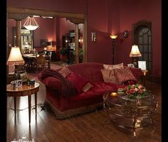 a living room filled with red couches and lamps on top of it's sides