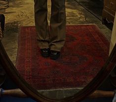 a person standing in front of a mirror on top of a rug with their legs crossed