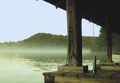 a dock with water and trees in the background on a foggy day at dusk