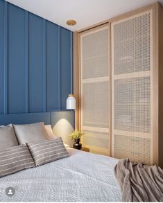 a bed sitting next to a blue wall and wooden headboard with white sheets on it