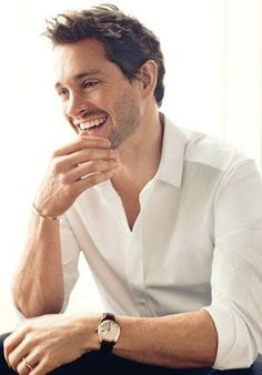 a man sitting down with his hand on his chin and looking at the camera while smiling