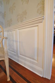 a white chair sitting on top of a hard wood floor next to a wooden door