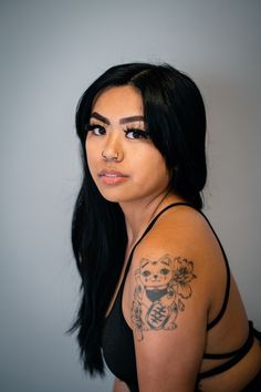 a woman with a tattoo on her arm and shoulder is looking at the camera while wearing a black tank top