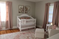 a baby's room with a white crib and pink drapes on the windows