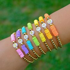 a woman's arm with different colored bracelets on it and gold beads around the wrist