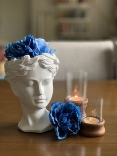 a white head with blue flowers on it sitting next to a candle and some candles