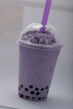 a purple drink with black spots on the rim and a purple straw sticking out of it