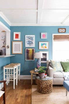 a living room with blue walls and pictures on the wall above the couch, coffee table