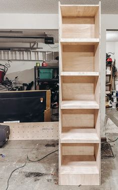 an unfinished shelf in a garage with tools and other items on the floor behind it