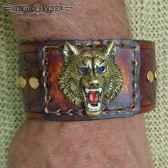 The Wolf Leather Cuff Expertly hand-made by an elder veteran who crafts a little of himself in every cuff: "This is a leather bracelet. It is unisex but was designed for men. It is 1.5" wide. It has a concho, as pictured. My bracelets are made to fit a wrist the size you specify. They are bigger than what you specify as they have to be in order to fit a wrist in esize your order."To measure your wrist, wrap a piece of string around your wrist and then measure the length of the string laying flat Custom Handmade Leather Bracelets, Handmade Custom Leather Bracelet, Handmade Vintage Leather Wristband, Unique Brown Concho Bracelet, Brown Leather Bracelet With Concho, Leather Concho Bracelet As Gift, Unique Leather Concho Bracelet For Gift, Unique Concho Leather Bracelet Gift, Unique Concho Cuff Bracelet For Gift