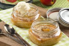 two jars filled with food sitting on top of a wooden table next to spoons