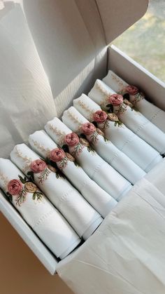 a box filled with lots of white napkins covered in pink and green flowers on top of each other