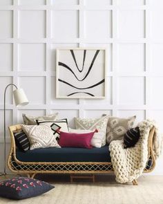 a living room filled with furniture and pillows on top of a wooden floor next to a white wall