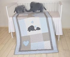 two stuffed elephants sitting on top of a crib next to a baby bed with a blanket