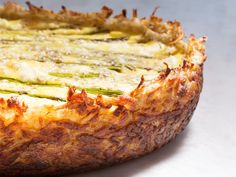 a quiche with cheese and asparagus is shown on a white tablecloth