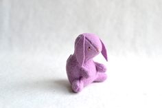 a purple stuffed animal sitting on top of a white surface