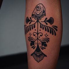 a black and white tattoo on the leg of a woman's legs with fish