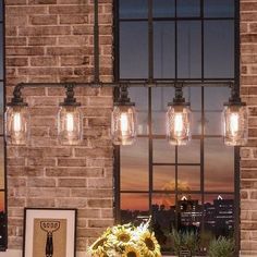 a dining room table with four lights hanging from it's sides and sunflowers in the center