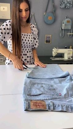 a woman standing in front of a white counter top next to a pair of blue jeans