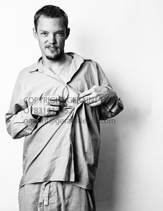 a black and white photo of a man holding something in one hand while standing against a wall