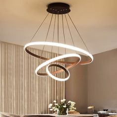 a modern chandelier hanging from the ceiling in a living room with white flowers