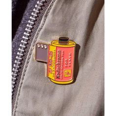 a yellow and red lighter pin sitting on top of a jacket