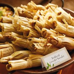 an assortment of tamales on a plate with a name tag in front of them