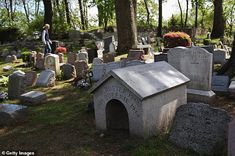 there is a small dog house in the middle of this cemetery with many headstones