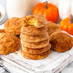 a stack of cookies sitting on top of a white plate next to pumpkins and milk