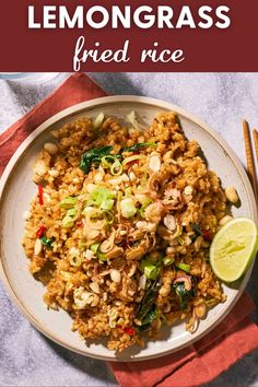 a white plate topped with fried rice next to chopsticks and a lime wedge