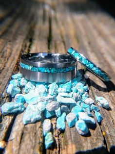 a couple of rings sitting on top of a wooden table next to rocks and stones