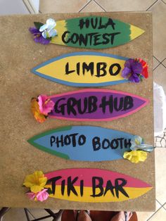 three surfboards with flowers on them sitting on a table next to a person's feet