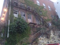 an old brick building with ivy growing on it's side and stairs leading up to the second story