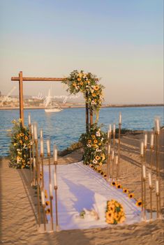 an outdoor ceremony set up on the beach with flowers and candles in front of it