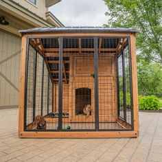 a dog kennel with two dogs in it on a brick patio next to a house