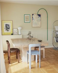 a table and chairs in a room with pictures on the wall above it, along with other furniture