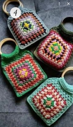 four crocheted purses sitting on top of a gray surface next to each other