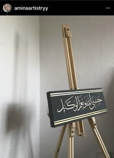 an easel with arabic writing on it in front of a white wall