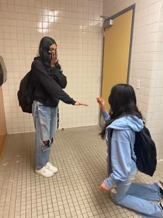 two women in a bathroom with one pointing at the other