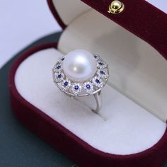 House of Pearls Boutique presents a timeless and luxurious pearl ring. Crafted with a 13-14mm Freshwater Pearl, adorned with a blue gemstone, this AAAA ring is truly an exquisite piece. Wear it for your special day or for an elegant evening look. Perfect for bridal parties and special occasions, the Luxury Ring-AAAA allows you to stand out from the crowd in style. Add a touch of extravagance to your jewelry collection and make memories that will last a lifetime. White 13-14mm Freshwater Pearl Ri Luxury Pearl Ring For Gift, Luxury Pearl Ring As A Gift, Elegant Pearl Ring With Birthstone, Elegant Pearl Birthstone Ring, Elegant Round Cabochon Sapphire Ring, Elegant Blue Pearl Ring With Gemstone, Luxury Oval Pearl Ring, Elegant Round Cabochon Pearl Ring, Blue Pearl Ring For Anniversary