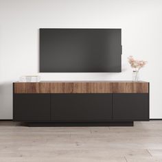 a large flat screen tv mounted to the side of a wooden cabinet in a white room