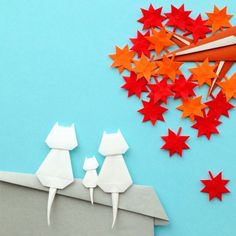 paper cut out of two cats sitting on top of a wall with red and orange stars