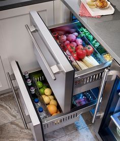 an open refrigerator filled with lots of fresh fruits and vegetables next to a counter top