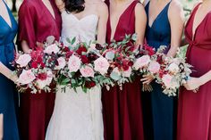 a group of women standing next to each other wearing dresses and holding bouquets in their hands