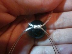 a person holding a wire wrapped around a black bead