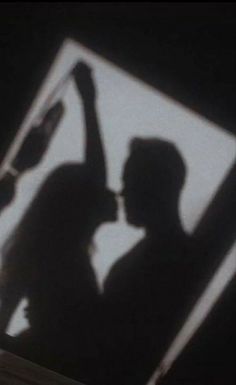 the shadow of two people standing in front of a mirror with their hands up to one another